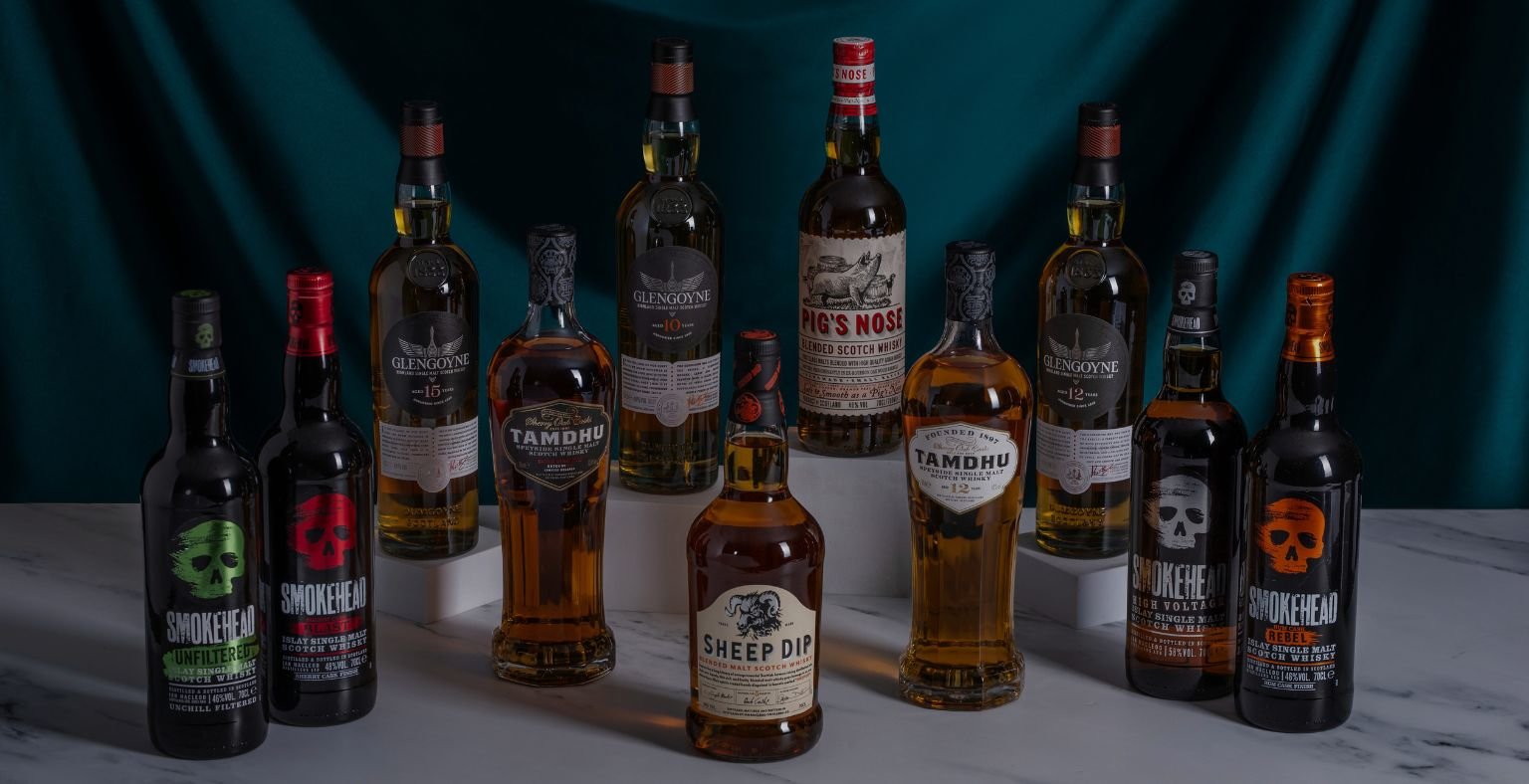 Twelve bottles of premium whiskies on white surface