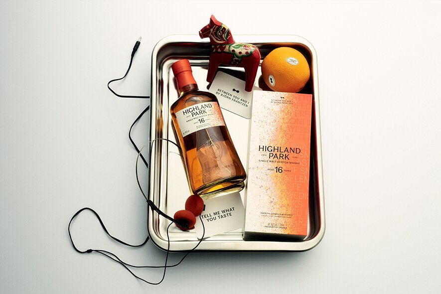 A bottle of Highland Park - Between You & I in a metal tray with decorative objects.