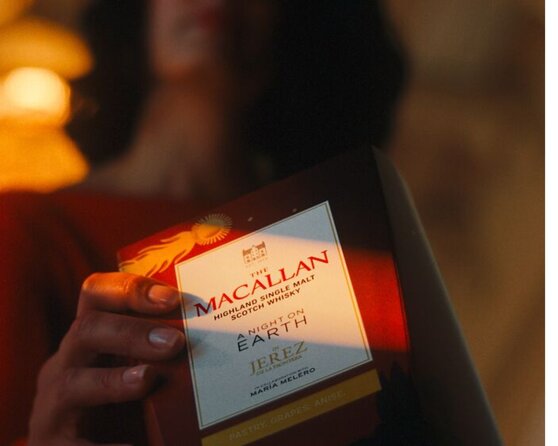 A woman holds up The Macallan A Night on Earth in Jerez presentation box