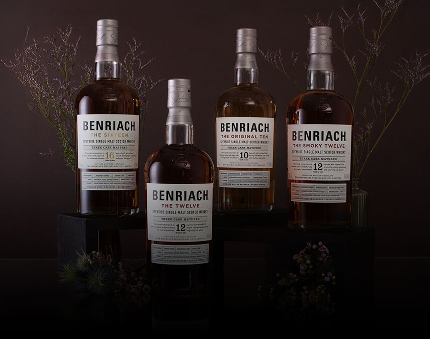 Four bottles of Benriach whisky surrounded by thistles on a brown background.