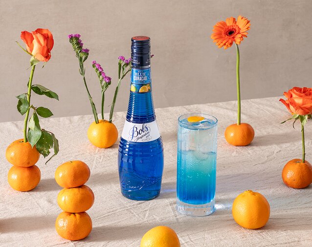 A Bols Blue Curacao Spritz with a bottle of Bols Blue Curacao next to it.