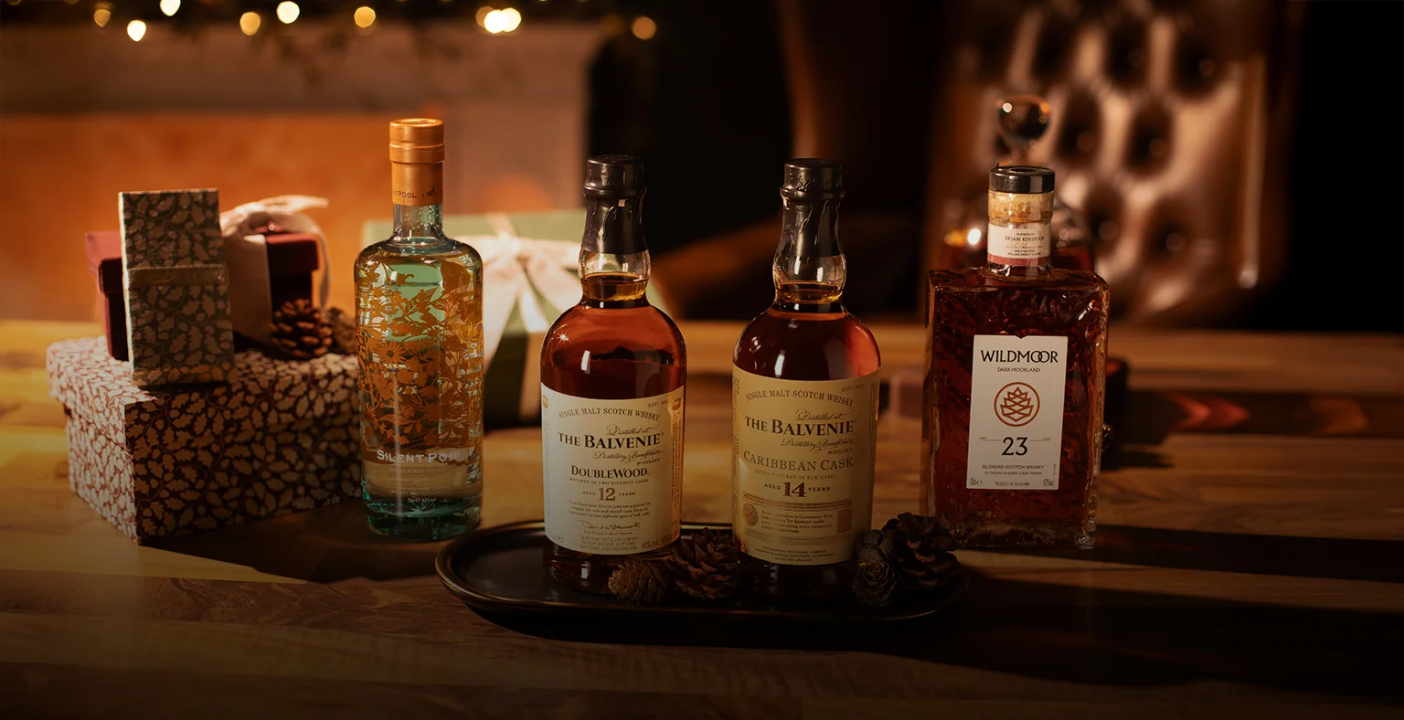 Four bottles of whiksy and gin on a christmas styled table.