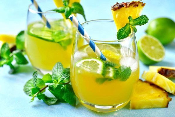 A rum punch cocktail garnished with fresh mint and pineapple.