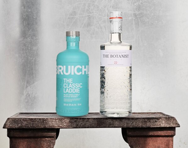 A bottle of Bruichladdich The Classic Laddie and The Botanist Gin on a stone bench.