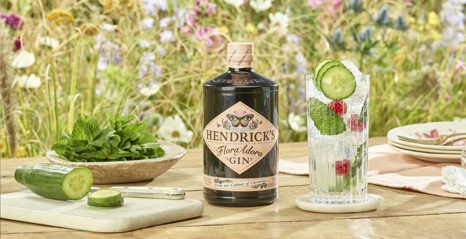 A bottle of Hendricks Flora Adora, a cocktail and garnishes on a table