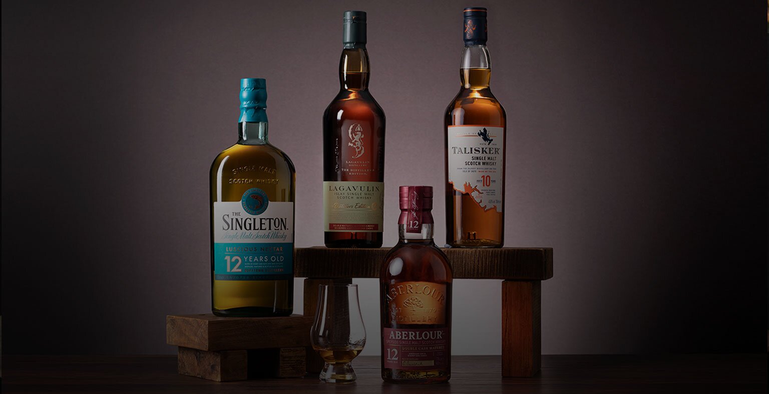 Four bottles of whisky against a light purple background.