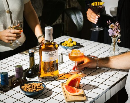 A bottle of Highland Park 18 Year Old on a party table with food and drink.