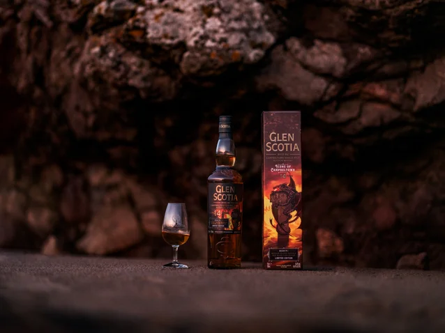 A bottle of Glen Scotia 14yo Icons #2 in a cave next to its presentation box and a dram of whisky in a tasting glass.