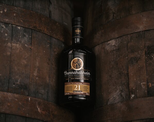 Image of a bottle of Bunnahabhain 21 Year Old Pedro Ximenez Cask Finish between two whisky barrels