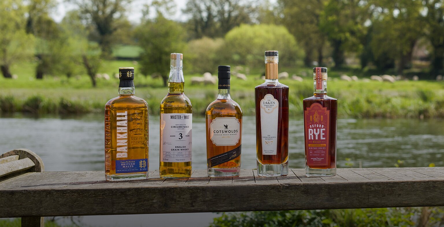 Five bottles of English whisky against a countryside background. 