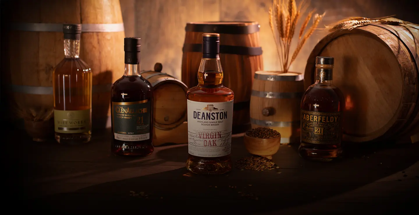 Four bottles of cask influenced whisky surrounded by barrels and barley.