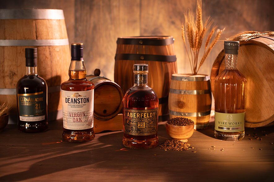 Four bottles of whisky surrounded by mini casks. 
