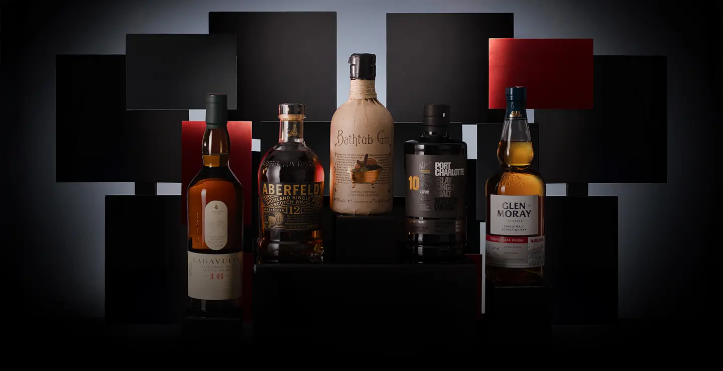 Five bottles of whisky and rum on a black background.