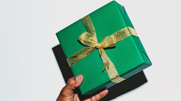 Hand holding up a Christmas gift wrapped in a bow.