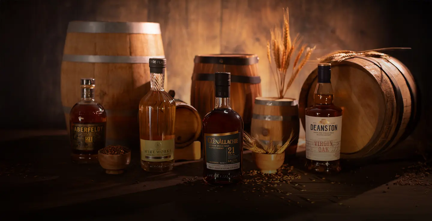 Four bottles of cask influenced whisky surrounded by barrels and barley.