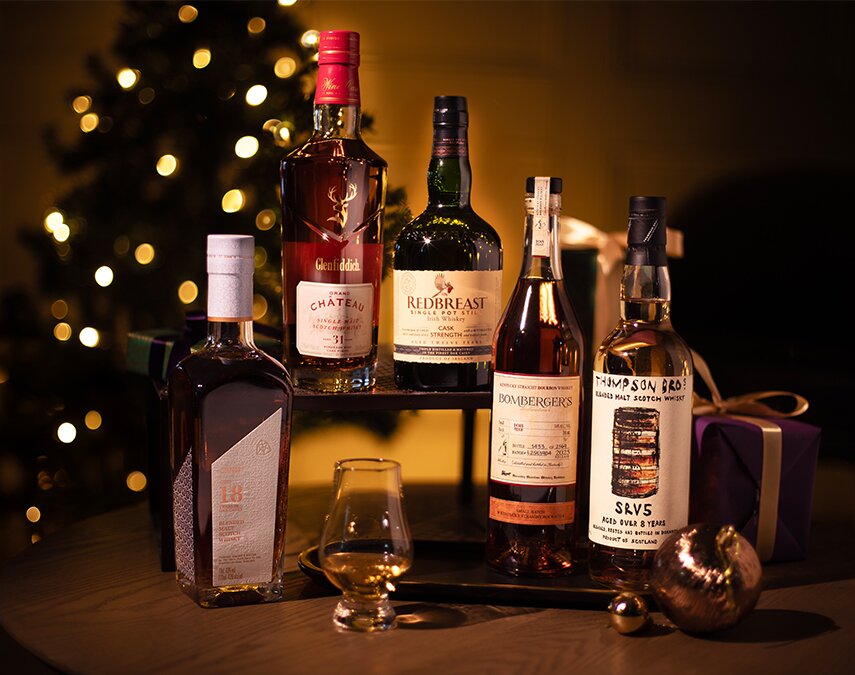 Five bottles of whisky in front of a Christmas tree.