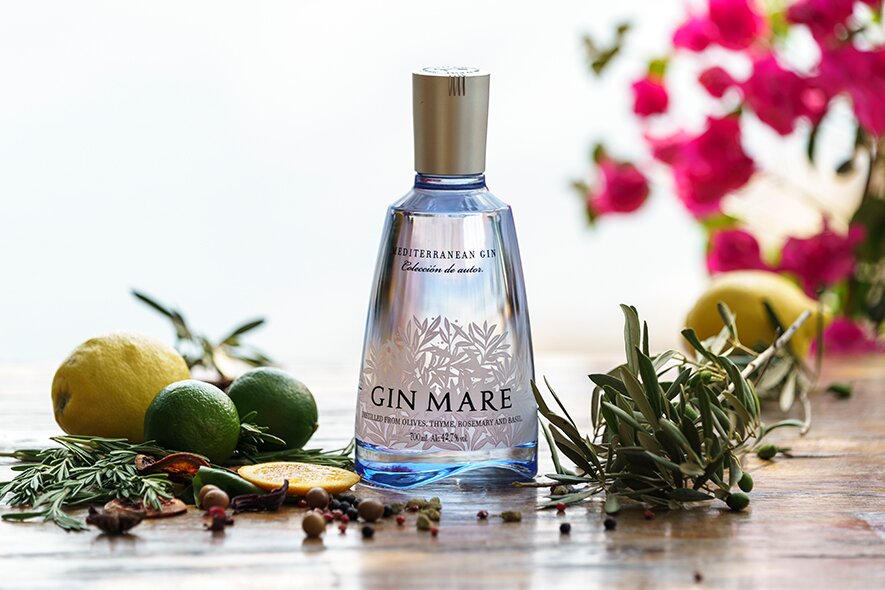 A bottle of Gin Mare Gin surrounded by botanicals. 