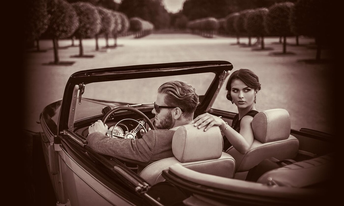 A photo of a couple in Italy sitting in a classic convertible car