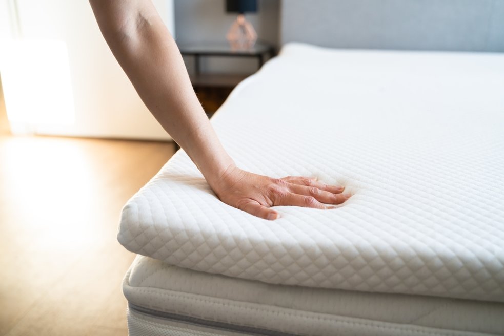 Hand pressing down on a mattress topper