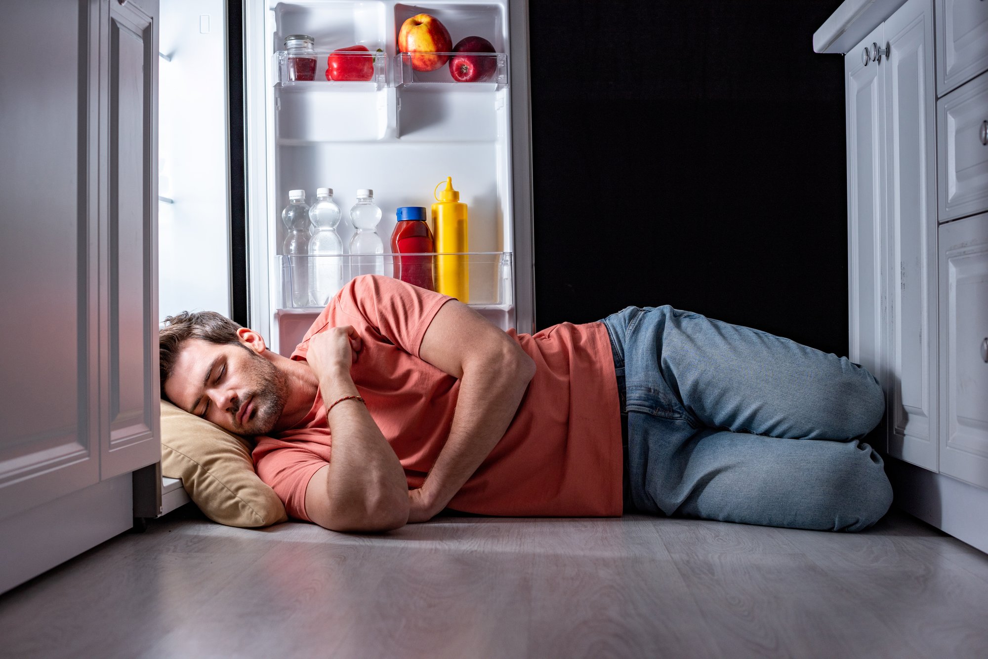 Man sleeping with his head on a pillow in the refrigerator