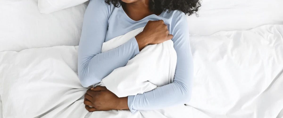 Woman in bed hugging the comforter