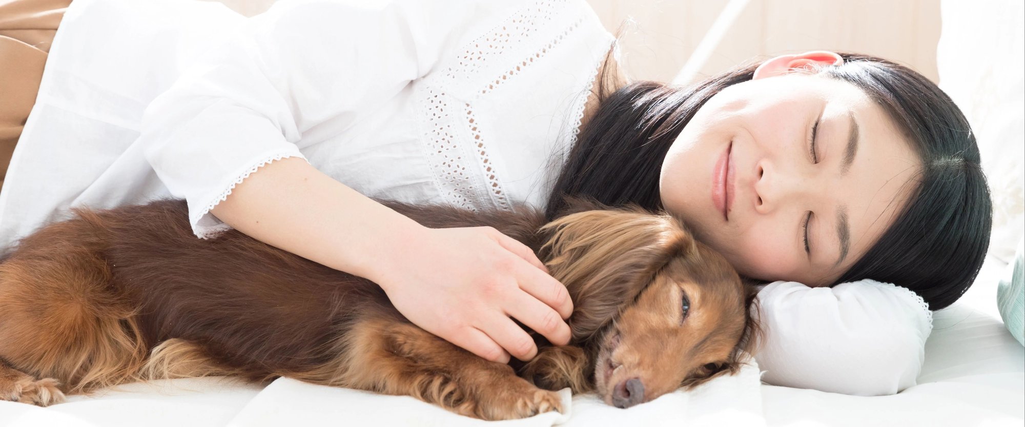Woman sleeping and cuddling with dog
