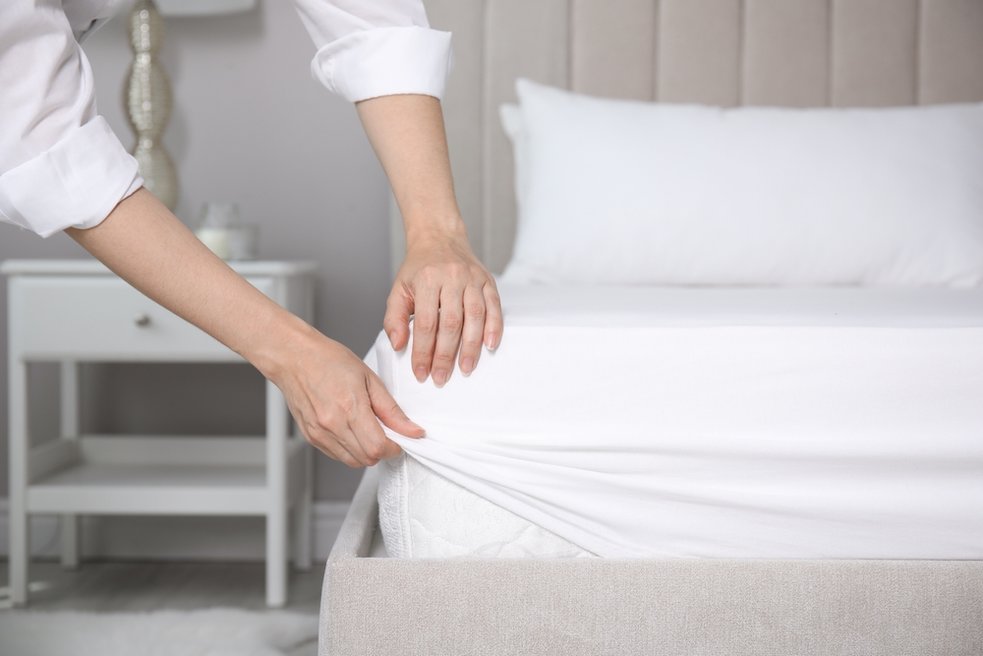 Woman putting a white fitted sheet on a mattress
