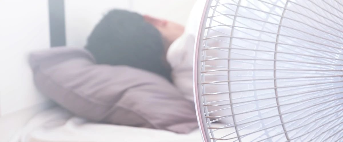 Man sleeping next to a bedroom fan