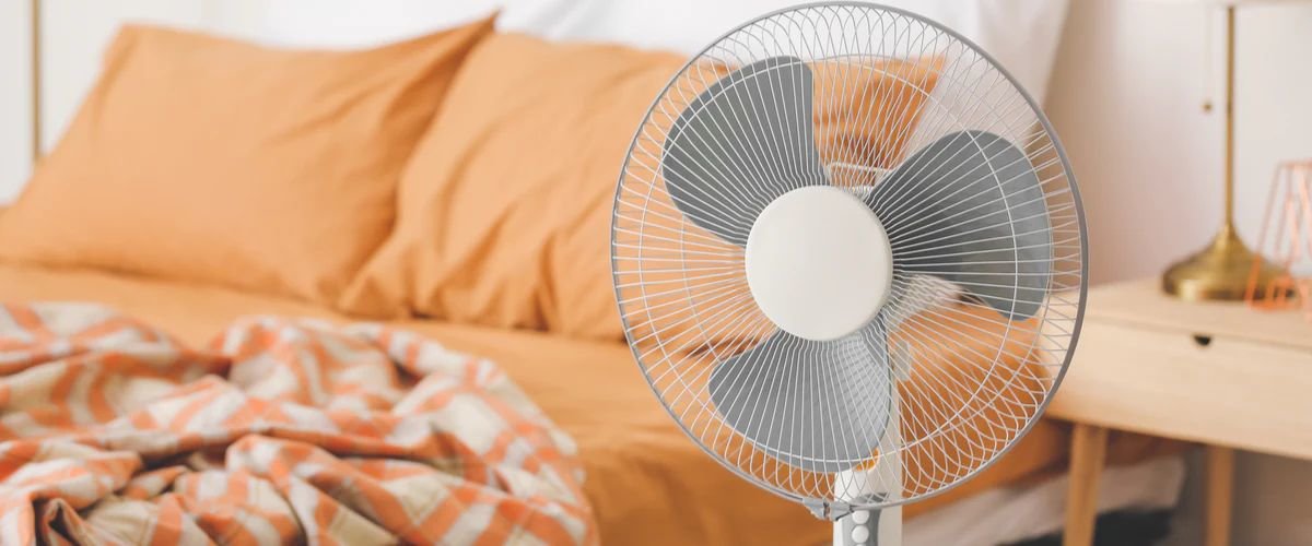 Standing fan in front of bed