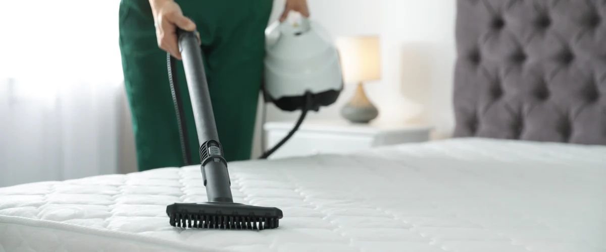 Woman vacuuming the top of a mattress