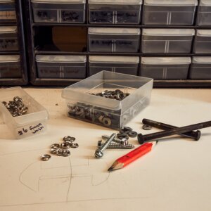 Various nuts, bolts, and fasteners on a table with a pencil