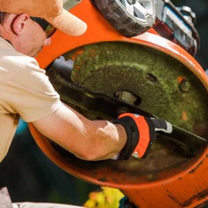 Man pointing at a lawn mower blade on the underside of a lawn mower