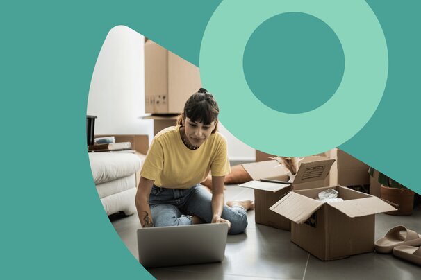 woman on laptop while unpacking boxes