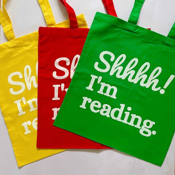 Yellow, red and green cotton tote bags with the slogan Shhh! I'm reading