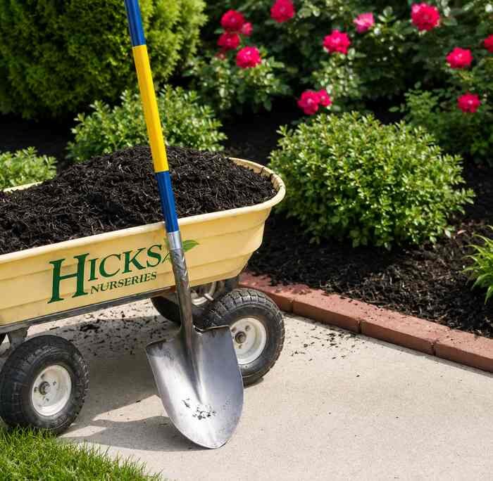 Mulch in a yellow cart near a garden