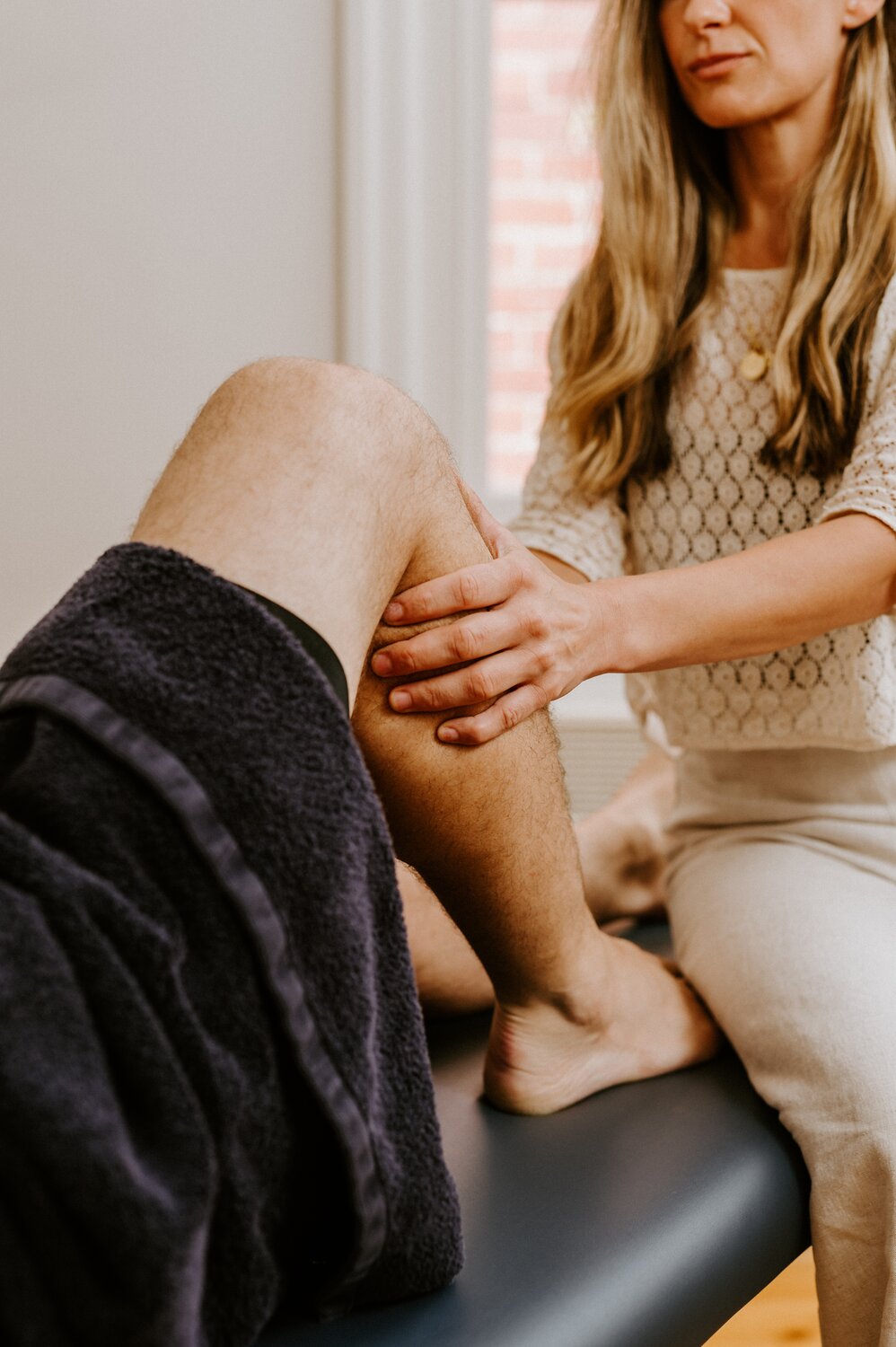 A close up photo of a patient having their calf muscle manipulated by a practitioner.