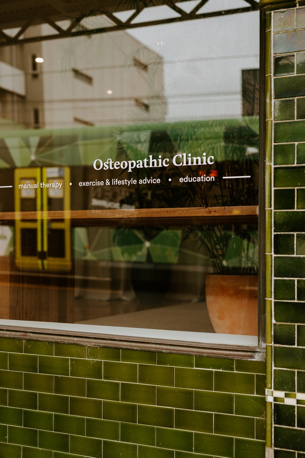 A close up photo of the Rhythm Health shop window, with a tram on High St visible in the reflection of the glass.