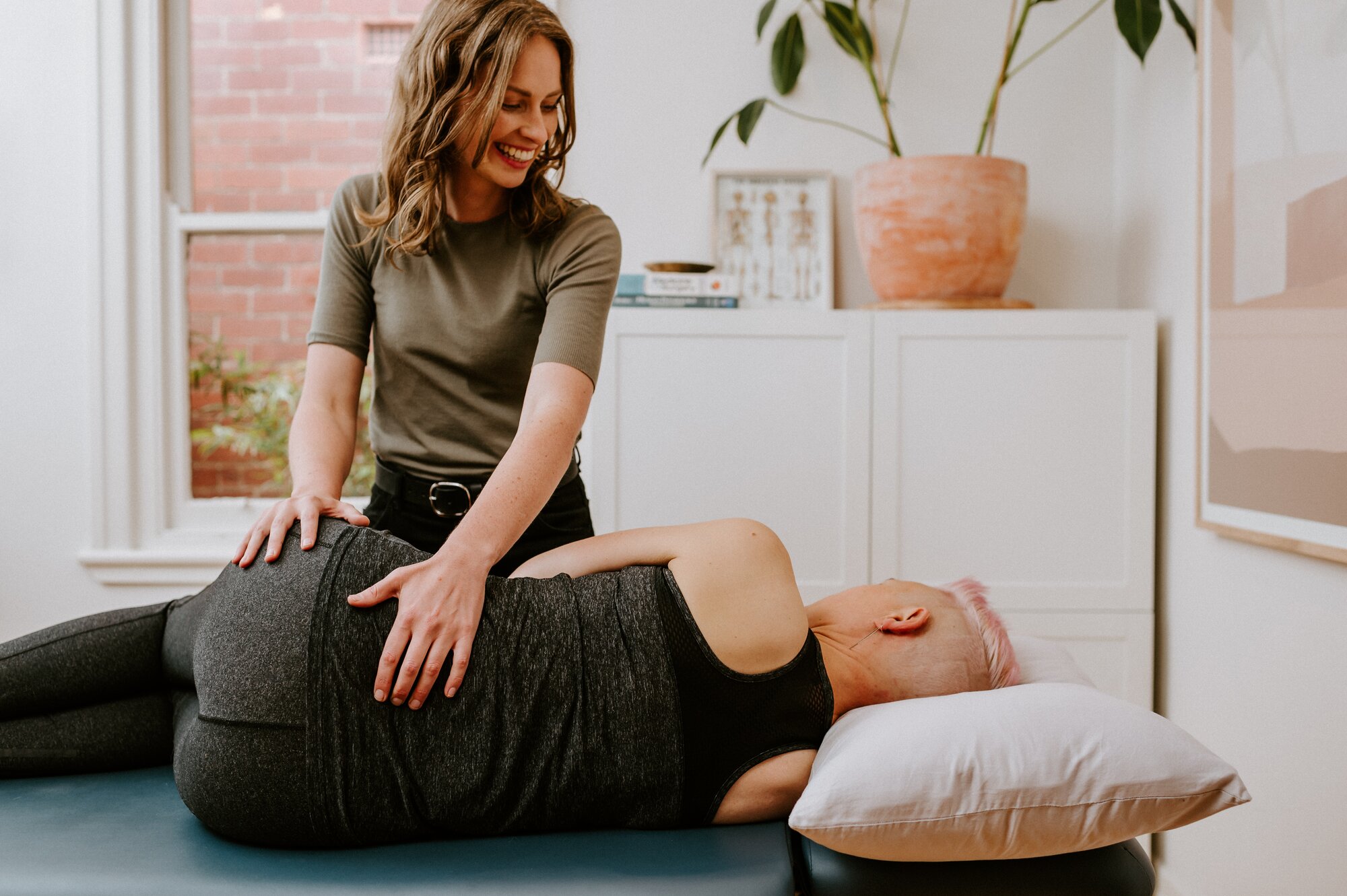 An Osteopath treating a woman side-lying on a treatment table.