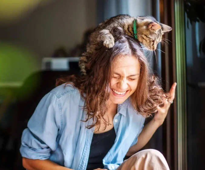 Photo of a woman with a cat on her shoulder