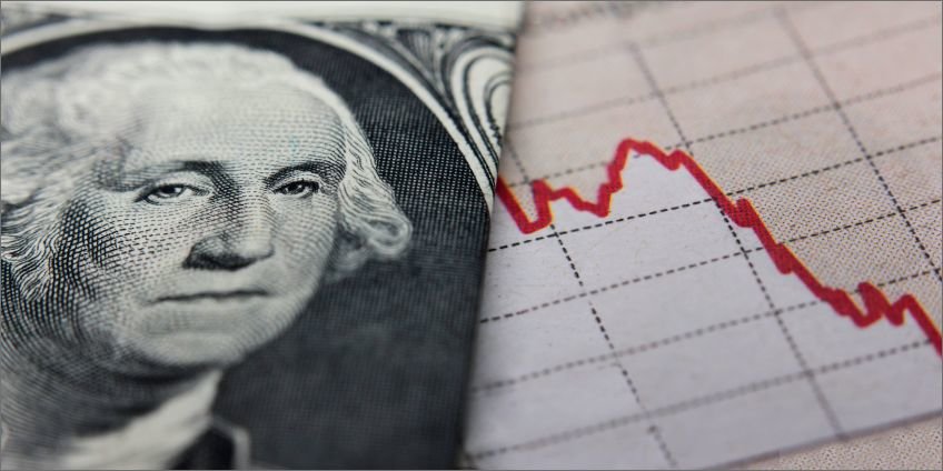 Close-up image of George Washington's face on a dollar bill next to a falling graph