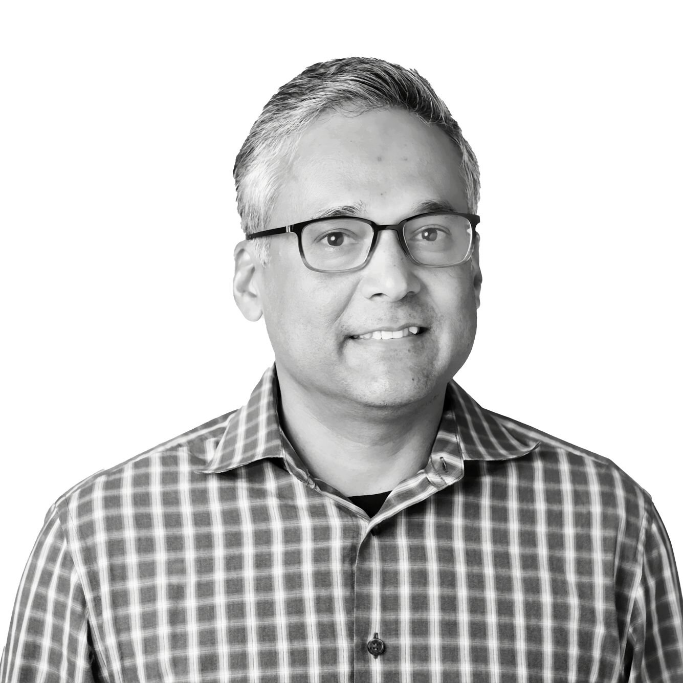 Rahul Roy-Chowdhury Indian-American middle-aged man. He is wearing glasses and a plaid shirt, with short hair neatly styled. He is smiling warmly, looking directly at the camera, which creates an inviting and approachable impression. The monochromatic color scheme adds a classic feel to the portrait, emphasizing his friendly demeanor.