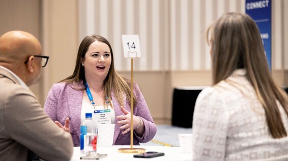 A woman addresses two people at a business meeting.