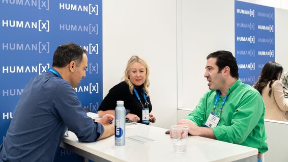 Three business people are huddled around a table, deep in discussion.