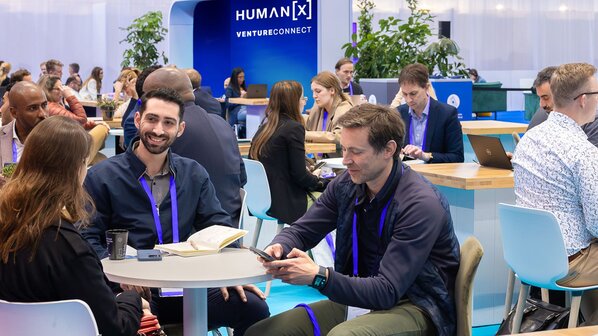 Attendees seated at tables, actively participating in VentureConnect meetings within a spacious conference room.