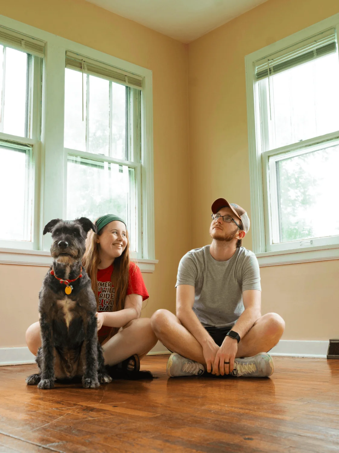 Young woman and man sitting on the floor in a house with a dog