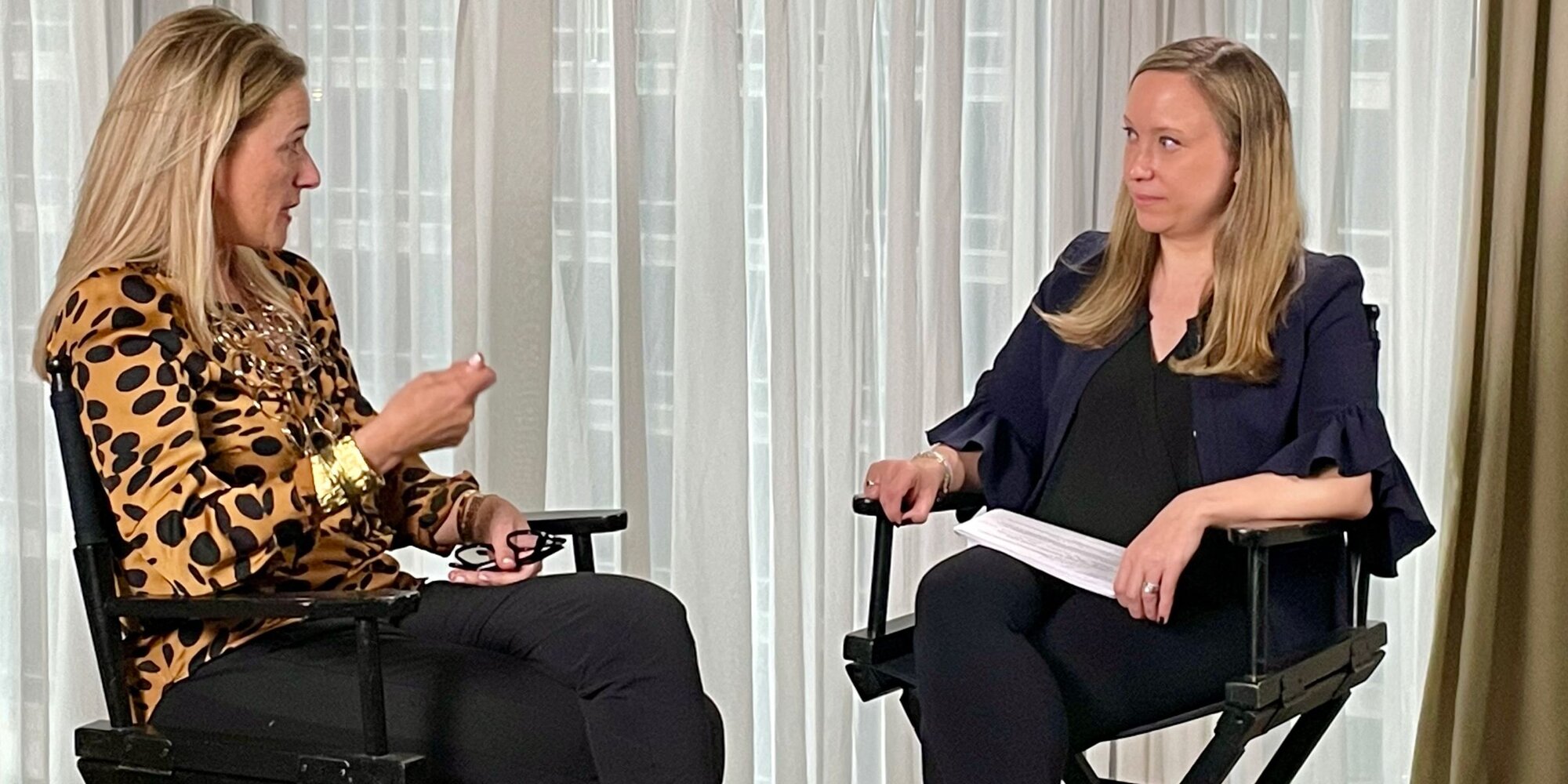 "Two women talking while sitting in chairs"