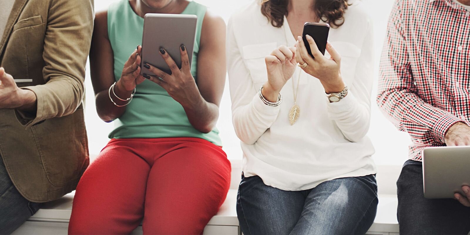 "four people sitting down holding devices"