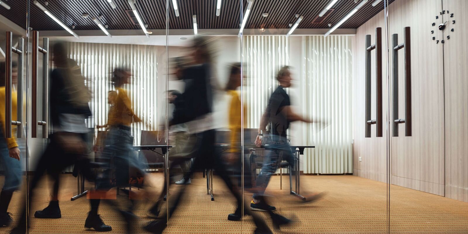 "Office room with blurred images of people walking back and forth"