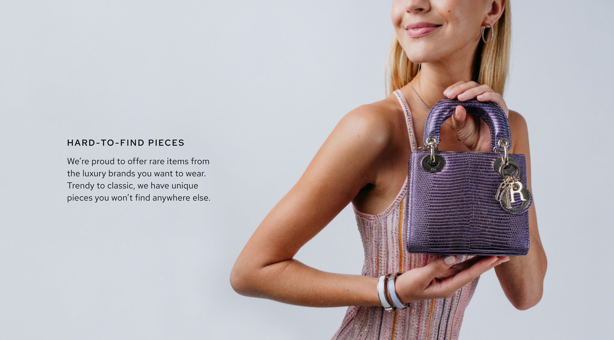 Photo of a woman wearing a dress, smiling, and holding a luxury handbag from Vivrelle. Text on image reads: "Hard-to-Find Pieces: We’re proud to offer rare items from the luxury brands you want to wear. Trendy to classic, we have unique pieces you won’t find anywhere else.”