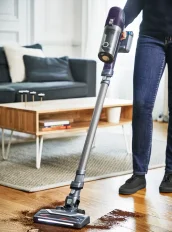 Aspirateur sans fil dans un salon lumineux. Électroménager en mensualités flexibles.
